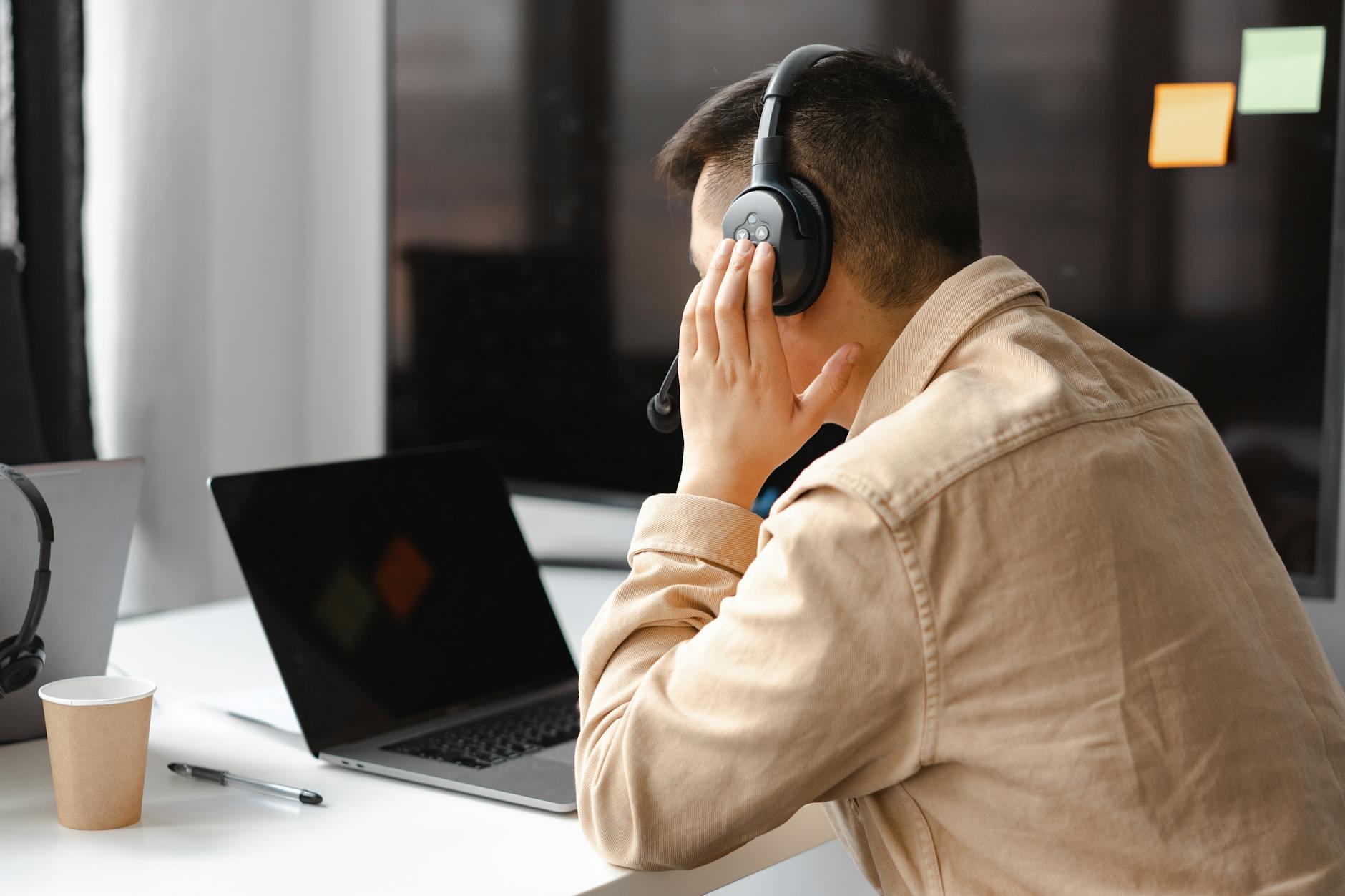 man wearing his headphone in front of his laptop